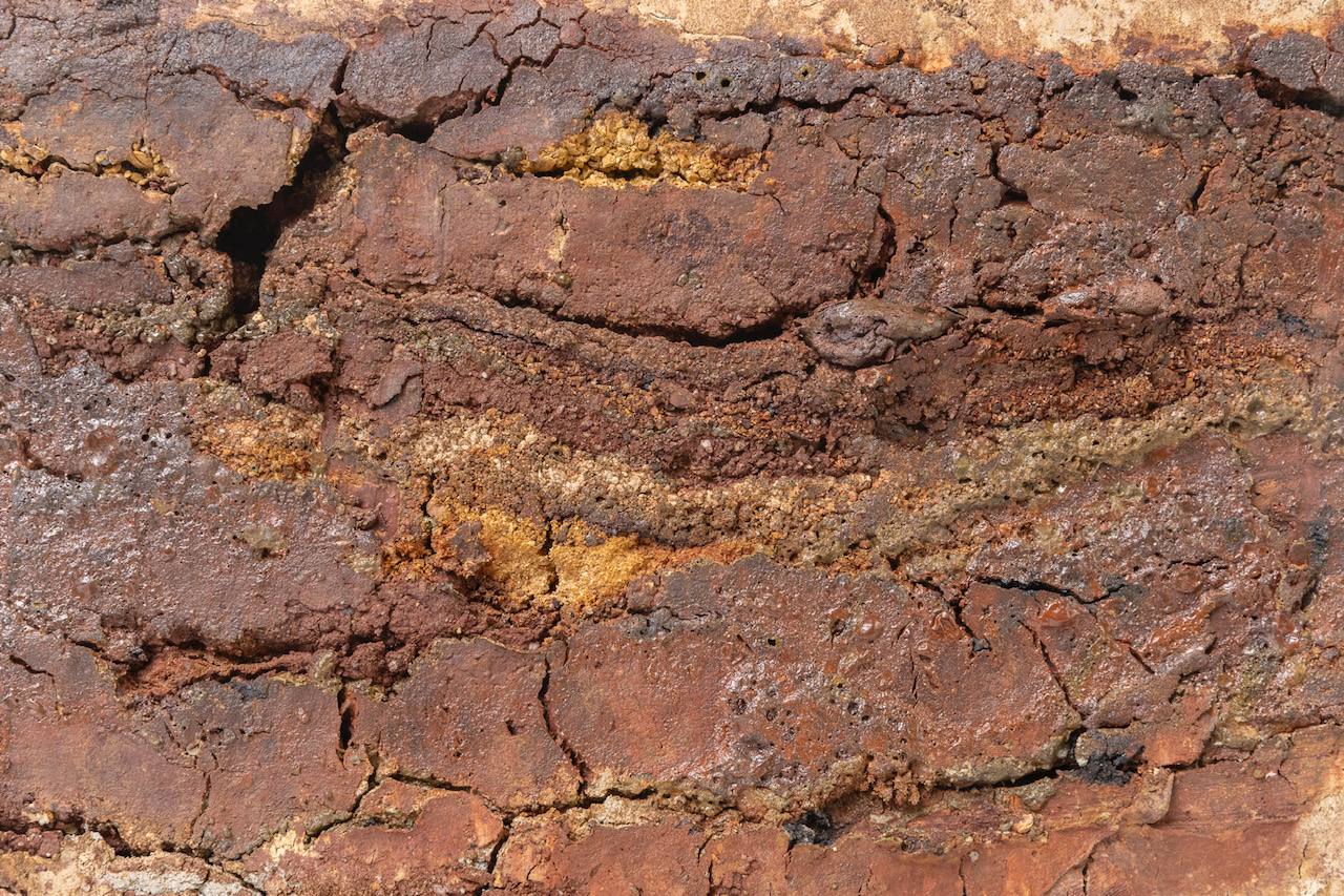 Detalle de un estrato de arcilla oxidada, con vetas ocres y rojizas.